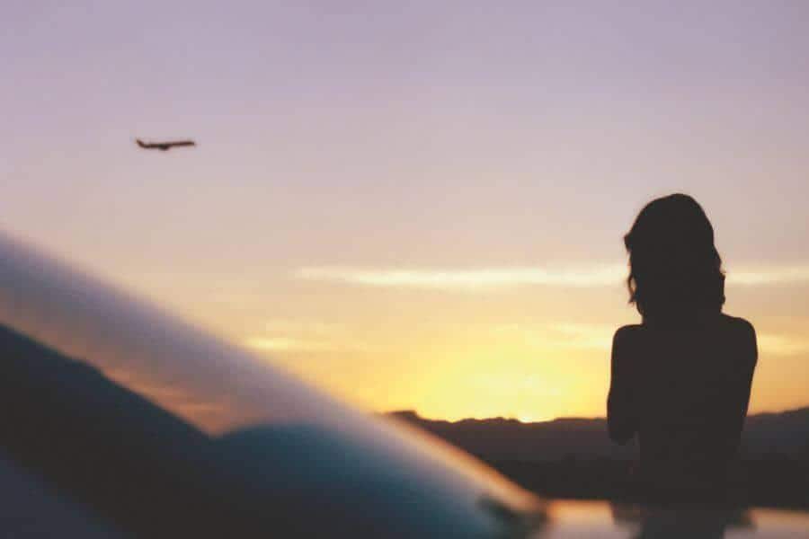 woman watching a plane take off at sunrise